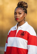 Woman wearing a red and white striped shirt with a logo against a blurred background