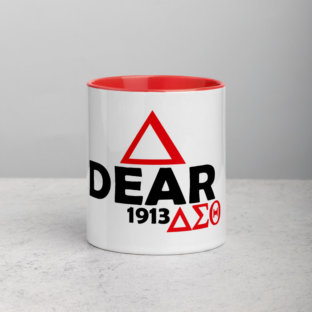 A white ceramic mug with a red and black 'Dear' text and a small red triangle logo on the side.